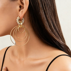 Close-up of gold geometric multi-layered hoop earrings with crystals on female model