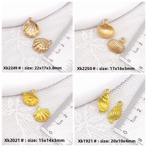 Detail view of golden alloy seashell pendants showing dimensions with a ruler