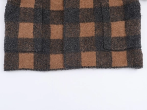Detailed close-up of checkered knit coat featuring dual front pockets and fuzzy texture