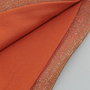 Macro shot of rust red knit fabric with metallic gold shimmer and mesh texture