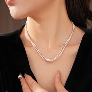 Close-up of a silver double-layered pearl necklace with a round metal pendant on a model