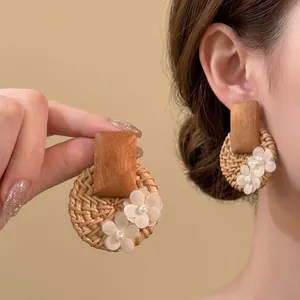 Detail of rattan woven drop earrings with wooden top and delicate white fabric flowers