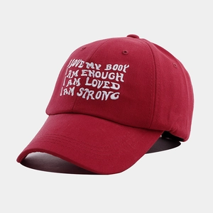 Detailed close-up of red cotton baseball cap featuring white motivational embroidery