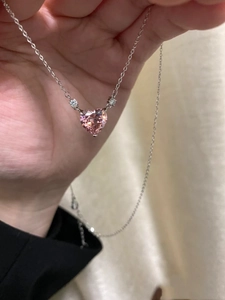 Close-up of pink heart-shaped crystal pendant with silver chain shown in hand