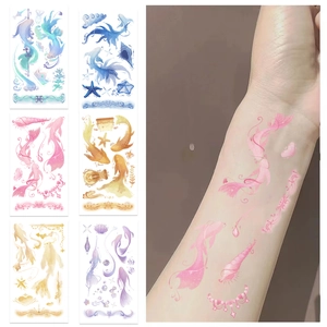 Close-up of colorful koi fish and seashell tattoo stickers applied to the arm skin