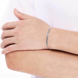 Gros plan d'un bracelet gourmette plate en acier inoxydable argenté porté au poignet