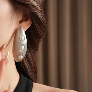 Boucles d'oreilles ovales argentées mates avec trois perles portées par un mannequin