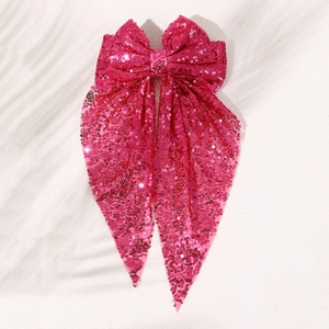 Detail of fuchsia sequin oversized bow hair clip with shimmering reflective surface