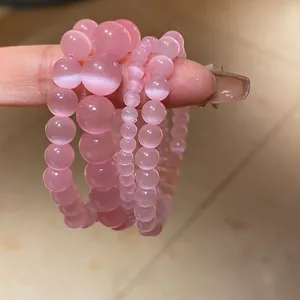 Pink cat eye stone beaded bracelets in four sizes displayed on a hand model