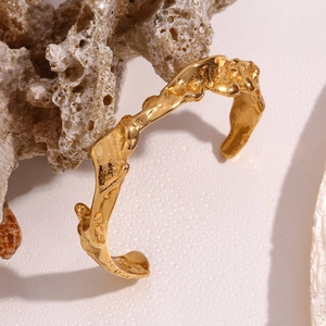 Detail of 18K gold-plated irregular wavy cuff bracelet on white coral stone