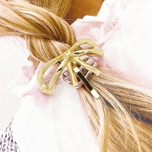 Elegant gold bow hair clip with hollow metal design shown on a braided hairstyle