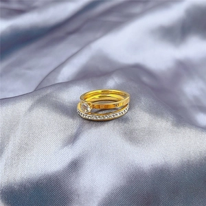 Detail of gold Roman numeral rings with crystal settings on silver silk background