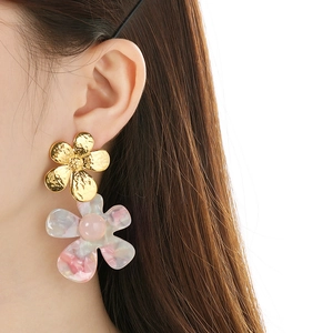 Close-up of golden hammered metal and pink marble resin double flower earrings on model