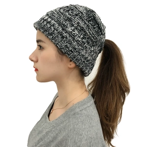 Detail view of knit ponytail beanie in black and white melange with top opening