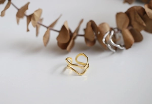 Detailed close-up of wave-shaped wide band rings in gold and silver finish