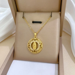 Close-up of a gold Virgin Mary pendant with crystals in a beige jewelry gift box