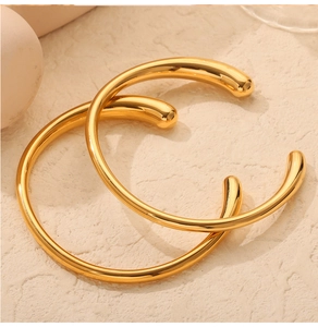 Detail of minimalist gold-plated titanium steel open bracelets with rounded teardrop ends