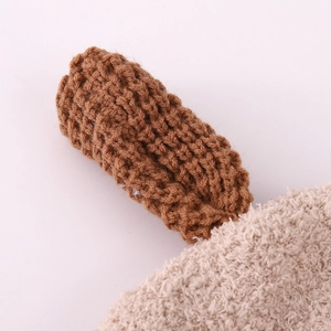Vue détaillée du tricot marron et de la doublure en peluche blanc cassé du bonnet enfant