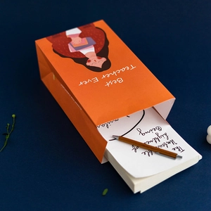 Cartoon orange teacher gift box with Best Teacher Ever print and pen on blue surface