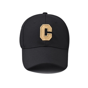 Close-up of golden embroidered letter C on black textured baseball cap with curved brim