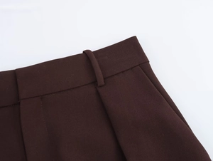 Makroansicht der dunkelbraunen Anzughose mit Bundfalten und Twill-Stoffstruktur