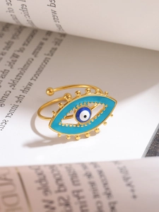 Macro detail of golden evil eye adjustable ring with enamel inlays on a book background