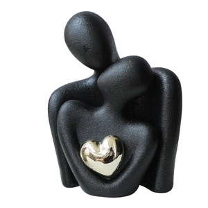 Modern minimalist abstract ceramic couple embrace sculpture in matte black with gold heart