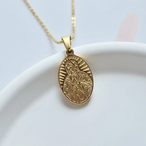 Détail macro du pendentif médaille Marie dorée sur une fine chaîne en acier inoxydable