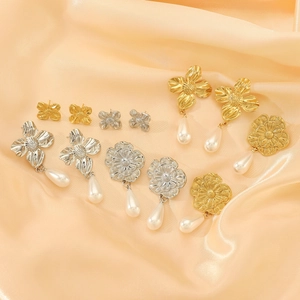 Detail of floral titanium earrings with teardrop pearls on champagne silk fabric