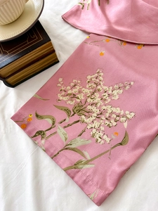 Dettaglio ravvicinato di tessuto in raso rosa con stampa floreale e trama setosa