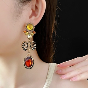 Detailed view of vintage bow earrings with yellow and red gemstones on a model