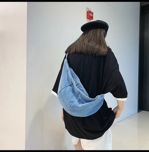 Blue denim crescent crossbody bag shown on model for a casual and oversized street style look