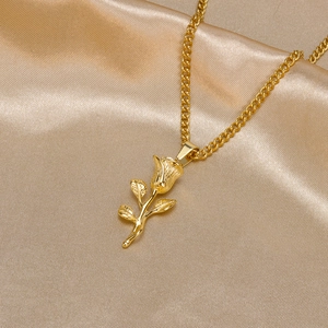 Detail of a 3D gold rose flower pendant on a sleek chain over champagne satin fabric