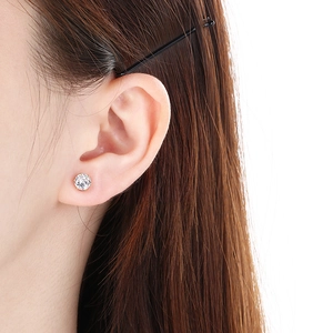 Close-up of a model wearing golden round stud earrings with sparkling clear zircons