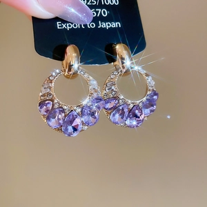 Dettaglio di orecchini dorati con cristalli viola e strass luccicanti ed eleganti