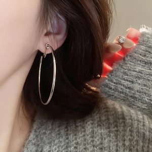 Close-up of a large silver hoop earring worn by a model in a minimalist style