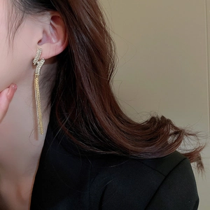 Detail view of lightning bolt earrings with long sparkling tassels on a model