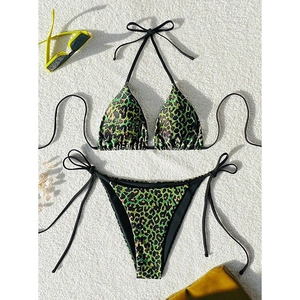 Detailed flat lay of green leopard print bikini with black ties and yellow sunglasses