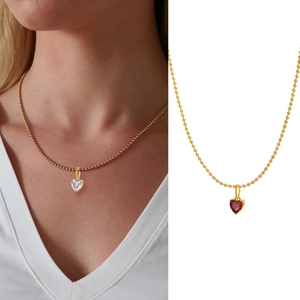 Detail of a gold heart pendant necklace featuring red and pink zircon stones on models