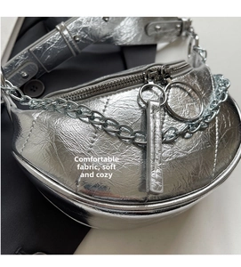 Macro shot of silver metallic pleated saddle bag showing chain strap and double zippers
