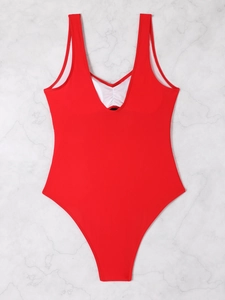 Detailed close-up of a red one-piece swimsuit with white ruffled trim and V-neckline