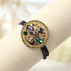 Détail d'un élastique baroque avec incrustations de cristaux colorés et pendentif doré