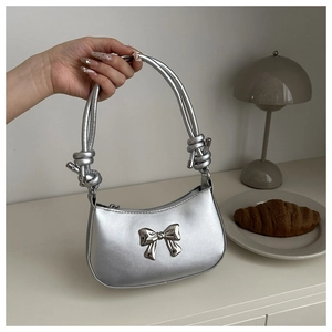 Detail of silver metallic handbag featuring 3D bow and stylish knotted shoulder strap