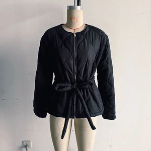 Detail of black wave-quilted jacket featuring round neck and adjustable waist tie belt