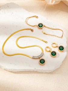 Detail of emerald titanium steel jewelry set with gold snake chains and crystals
