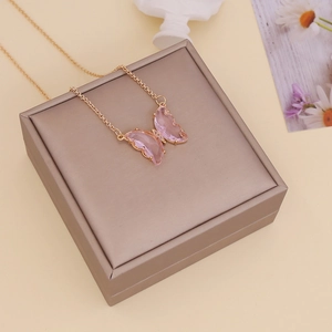Pink crystal butterfly necklace on rose gold jewelry box with aesthetic floral background