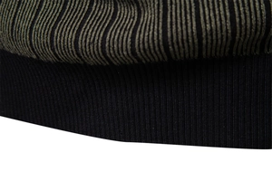 Close-up of the black ribbed cuff and green striped knit texture of the sweater