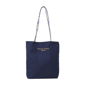 Large dark blue canvas tote bag with woven shoulder straps and metallic lettering