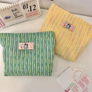 Détail de trousses de maquillage tissées avec motifs en maille et écussons mignons