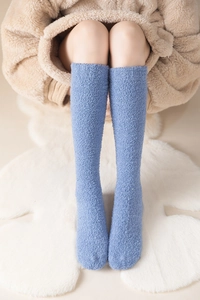 Close-up of soft blue coral fleece knee-high socks on a white fur rug for cozy winter warmth
